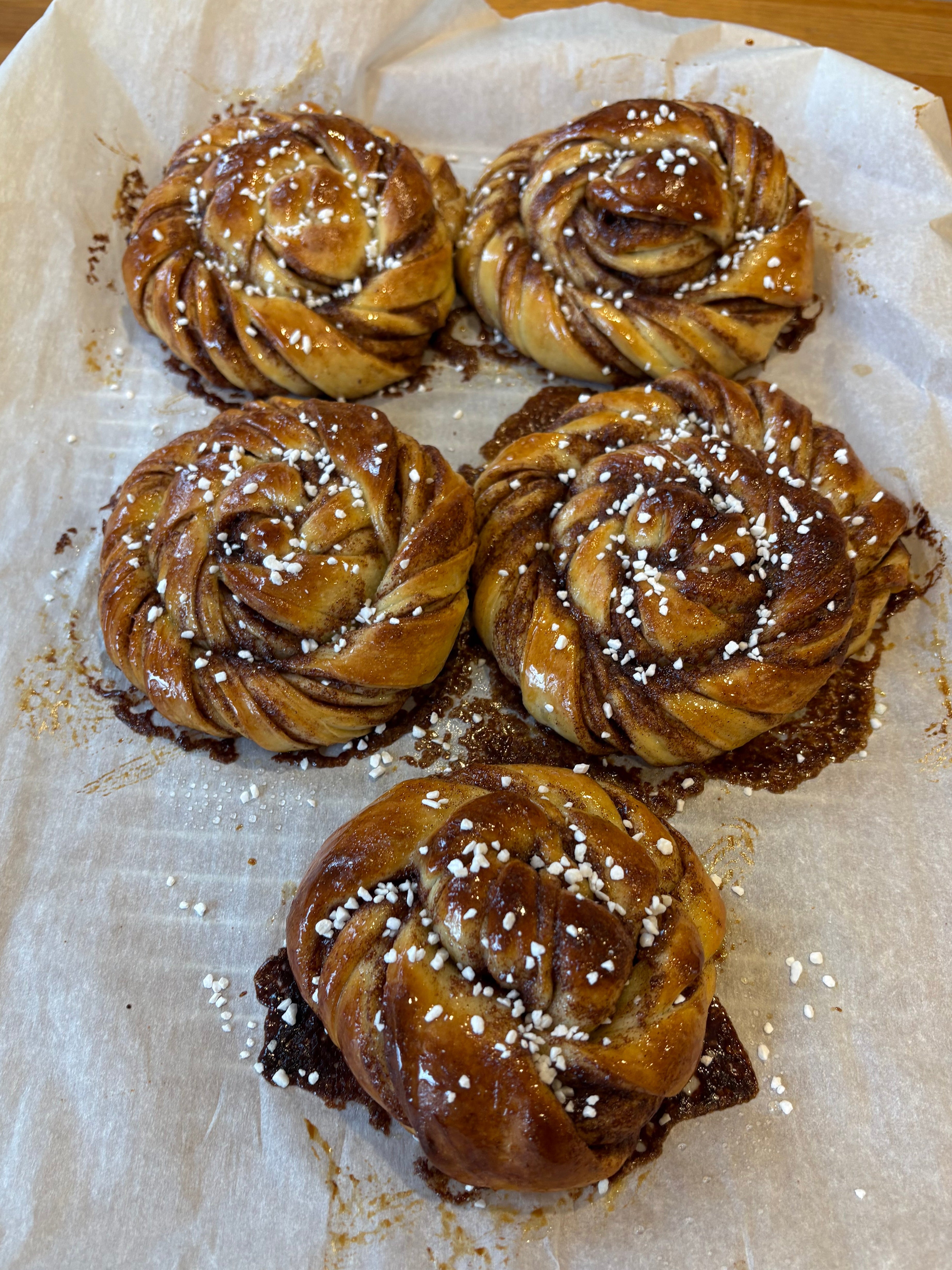 Five cinnamon rolls on a piece of parchment paper