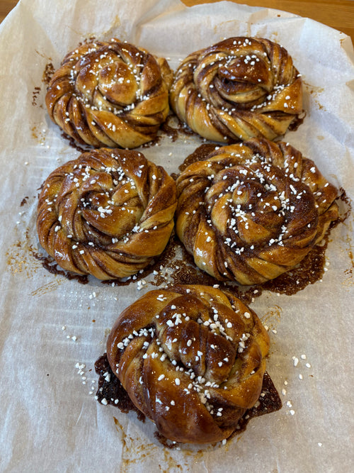 Five cinnamon rolls on a piece of parchment paper